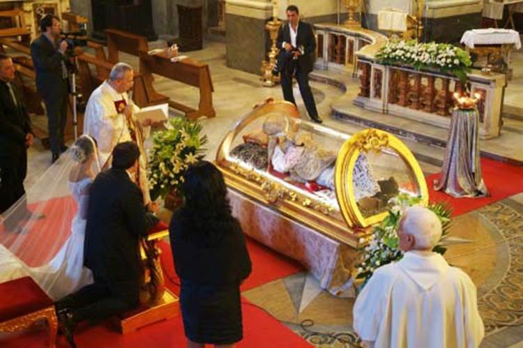 priest sayiing prayers to wax figure
